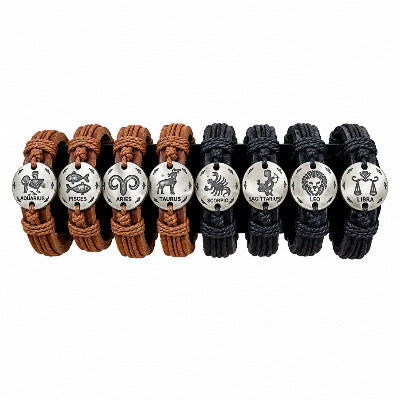 A set of twelve leather wrap bracelets displayed on a black stand against a solid tan background. The bracelets are arranged in two columns of six, featuring brown and black leather straps with silver-toned circular charms engraved with zodiac symbols: Aries, Taurus, Gemini, Leo, Virgo, Libra, Sagittarius, Capricorn, and Scorpio.
